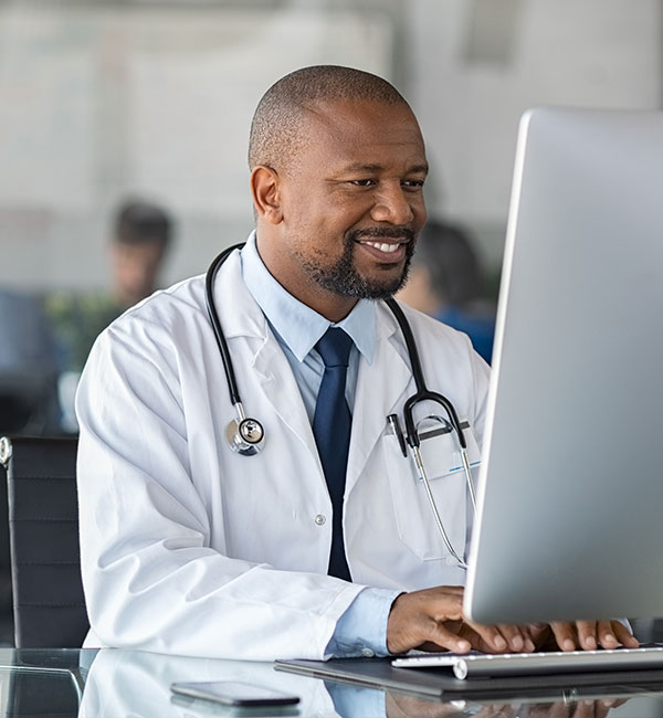 Male doctor smiling while typing on computer